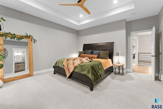 carpeted bedroom featuring a raised ceiling and ceiling fan