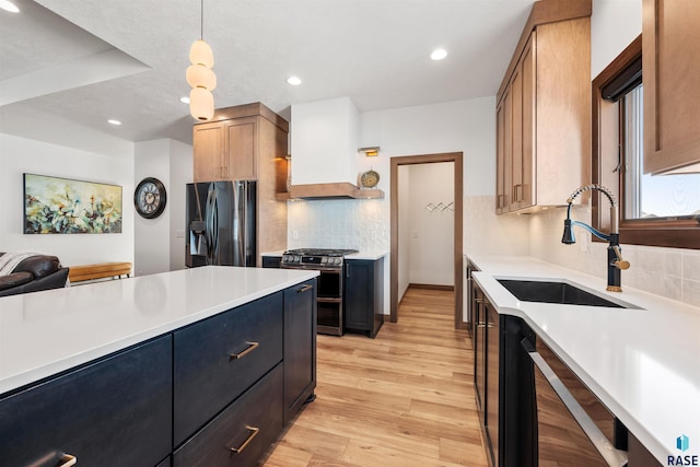 kitchen featuring sink, tasteful backsplash, decorative light fixtures, light hardwood / wood-style flooring, and appliances with stainless steel finishes