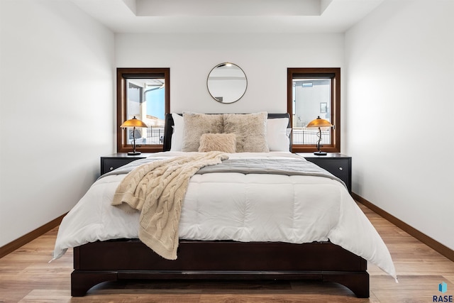 bedroom featuring a tray ceiling and light hardwood / wood-style floors