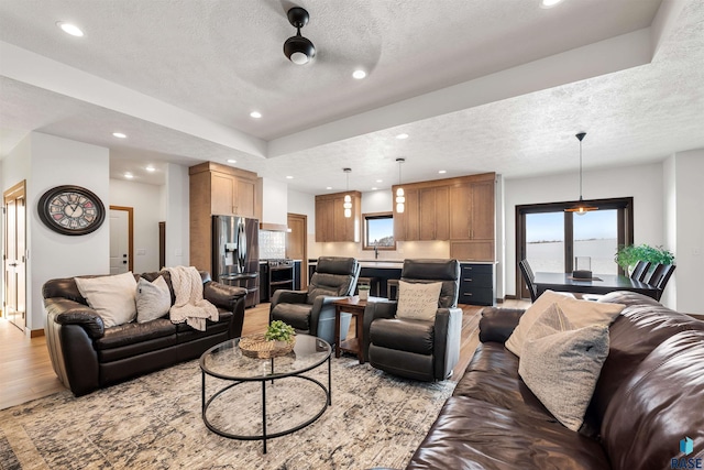 living room with sink, light hardwood / wood-style floors, and a textured ceiling