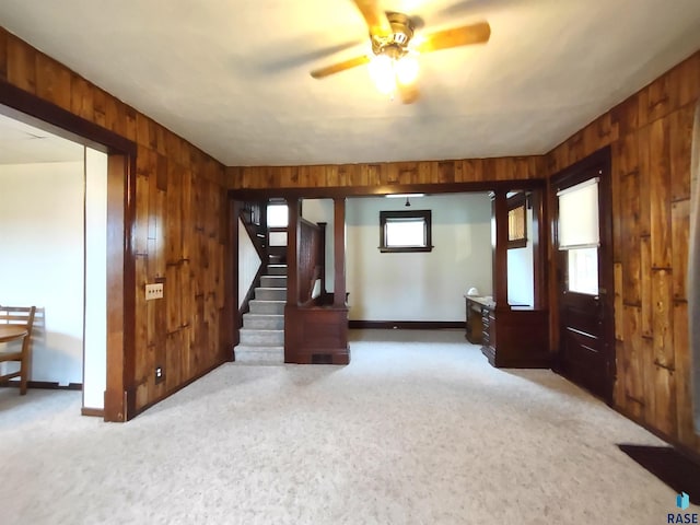 interior space featuring ceiling fan and wooden walls