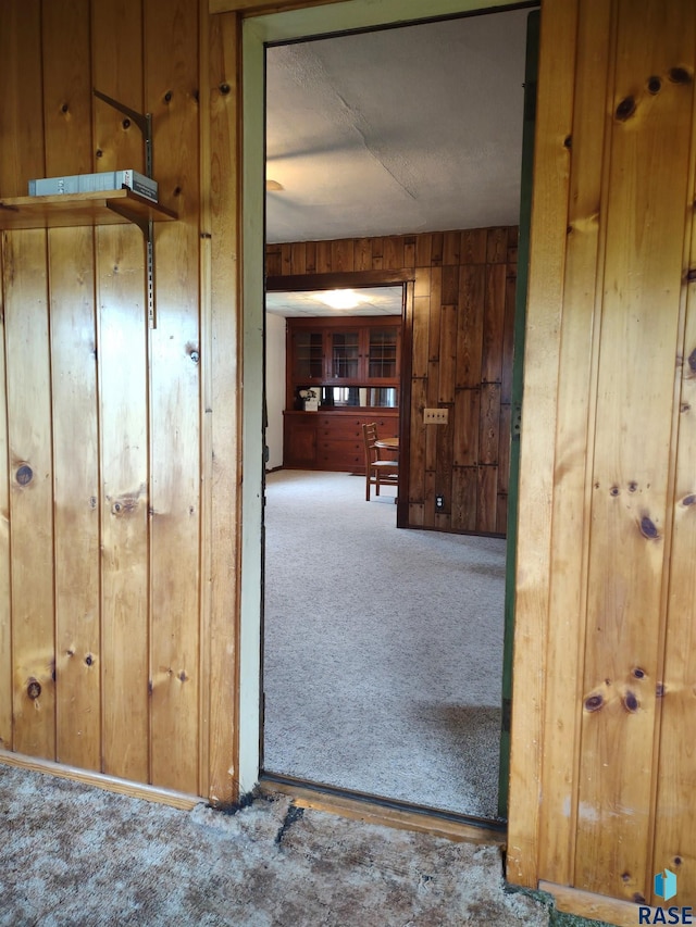 hall featuring carpet flooring and wood walls