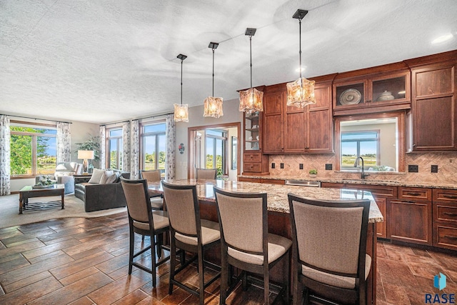 kitchen with tasteful backsplash, a breakfast bar area, light stone countertops, and hanging light fixtures