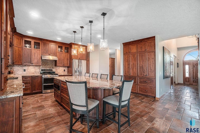 kitchen featuring pendant lighting, a breakfast bar area, appliances with stainless steel finishes, a center island, and decorative backsplash