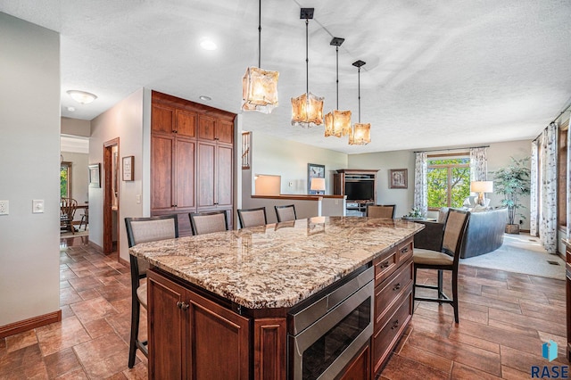 kitchen featuring stainless steel microwave, a kitchen breakfast bar, a center island, and decorative light fixtures