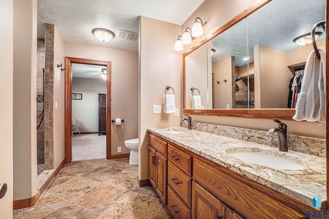 bathroom featuring walk in shower, vanity, toilet, and a textured ceiling