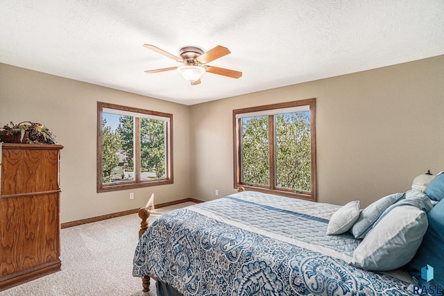 bedroom featuring multiple windows, ceiling fan, carpet flooring, and a textured ceiling