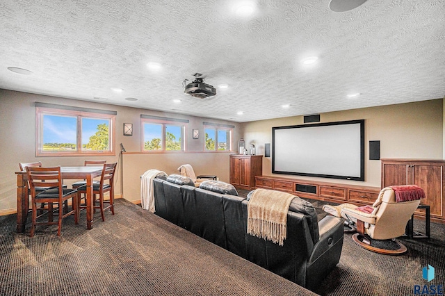 home theater room with a textured ceiling and dark colored carpet