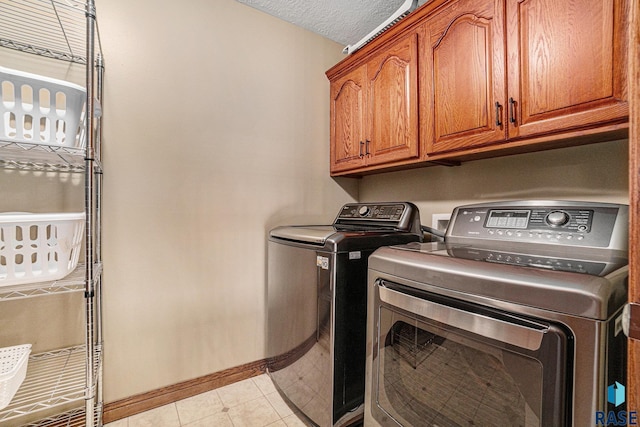 washroom featuring cabinets, a textured ceiling, and washer and clothes dryer