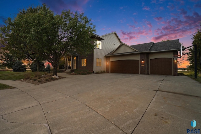 view of front of home with concrete driveway, brick siding, and an attached garage