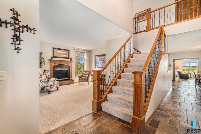 stairs with a high ceiling, carpet floors, and a healthy amount of sunlight