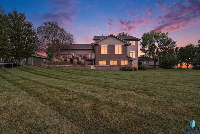 back of house at dusk with a lawn