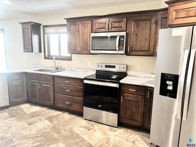 kitchen with dark brown cabinetry, stainless steel appliances, and sink