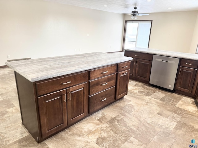 kitchen with light stone counters, dark brown cabinets, dishwasher, a kitchen island, and ceiling fan