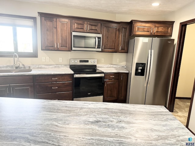 kitchen with sink, dark brown cabinets, and appliances with stainless steel finishes