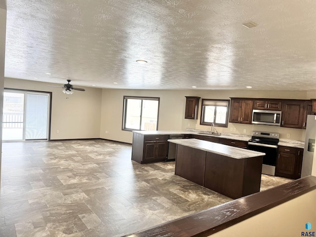 kitchen with stainless steel appliances, a center island, sink, and dark brown cabinets