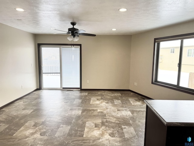 empty room with ceiling fan and a textured ceiling