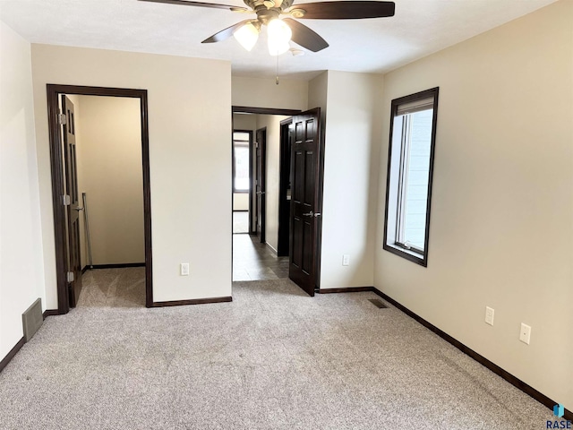 unfurnished bedroom featuring multiple windows, light colored carpet, and ceiling fan