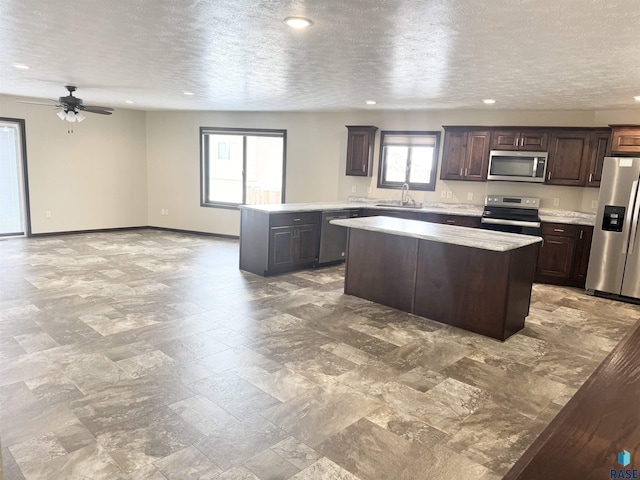 kitchen with dark brown cabinetry, sink, a center island, a textured ceiling, and stainless steel appliances