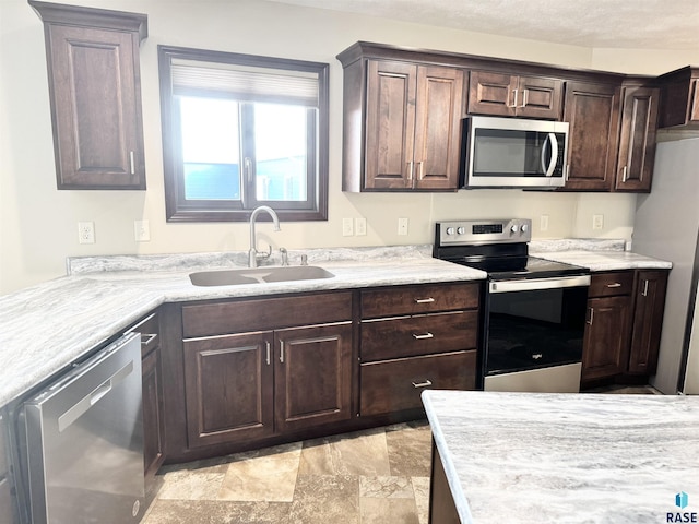 kitchen with dark brown cabinetry, sink, and stainless steel appliances