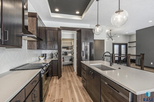 kitchen with decorative light fixtures, sink, a kitchen island with sink, light hardwood / wood-style floors, and stainless steel appliances