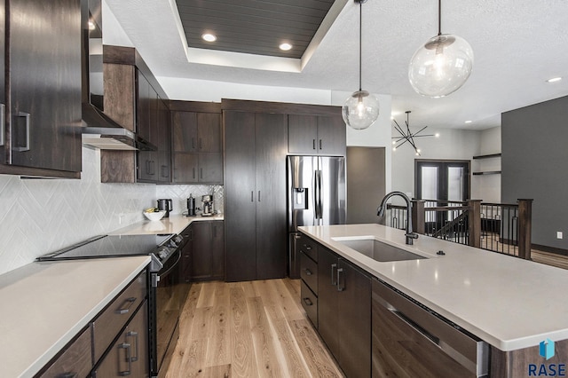 kitchen featuring sink, decorative light fixtures, light hardwood / wood-style flooring, a tray ceiling, and stainless steel appliances