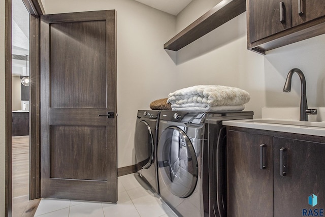 clothes washing area featuring independent washer and dryer, sink, cabinets, and light tile patterned floors