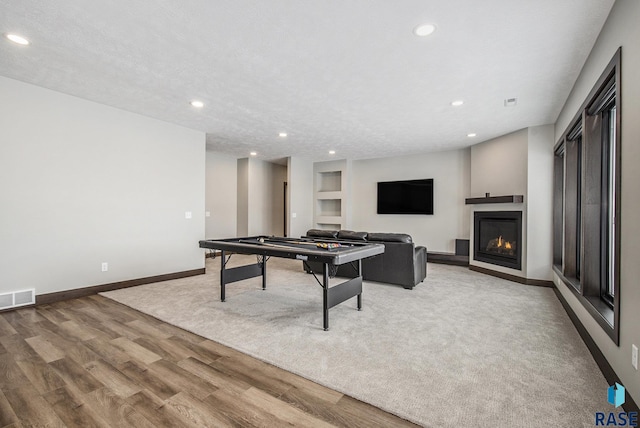 playroom with hardwood / wood-style flooring, built in shelves, and a textured ceiling