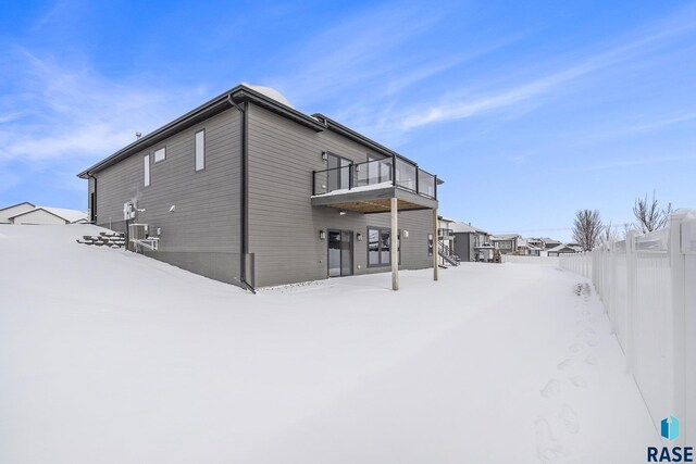 snow covered rear of property with a balcony