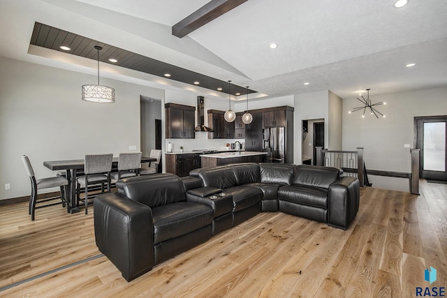 living room featuring a notable chandelier, light hardwood / wood-style flooring, lofted ceiling with beams, and a raised ceiling