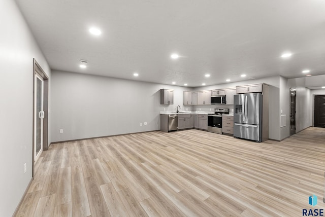 kitchen with appliances with stainless steel finishes, sink, gray cabinetry, and light hardwood / wood-style floors