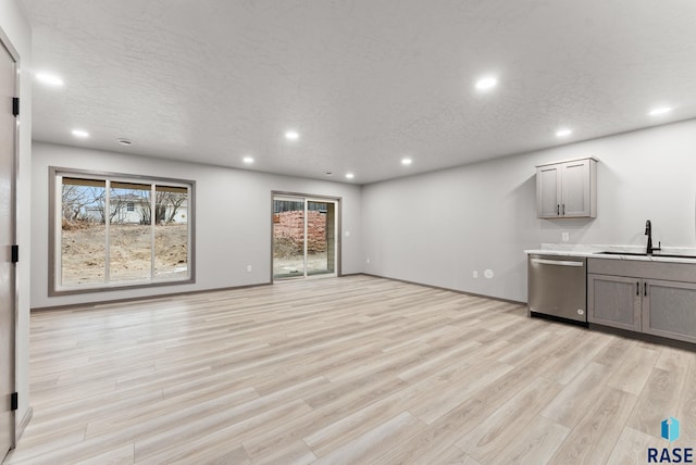 unfurnished living room featuring sink, a textured ceiling, and light hardwood / wood-style floors