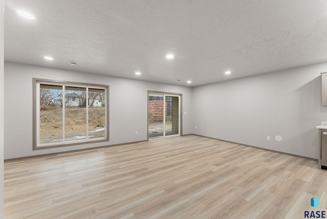 unfurnished living room featuring plenty of natural light, a textured ceiling, and light wood-type flooring