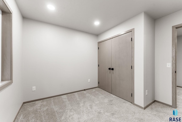 unfurnished bedroom featuring light colored carpet and a closet