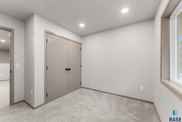 unfurnished bedroom with light carpet and a closet