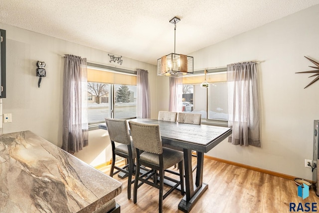 dining space featuring lofted ceiling, light hardwood / wood-style flooring, and a textured ceiling