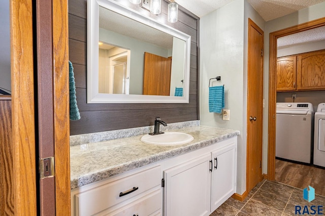 bathroom featuring vanity, washer and dryer, and a textured ceiling