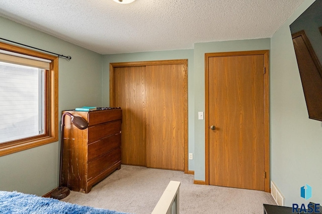 carpeted bedroom with a closet and a textured ceiling