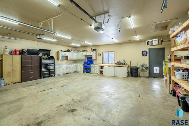 garage with a garage door opener, a workshop area, and an AC wall unit