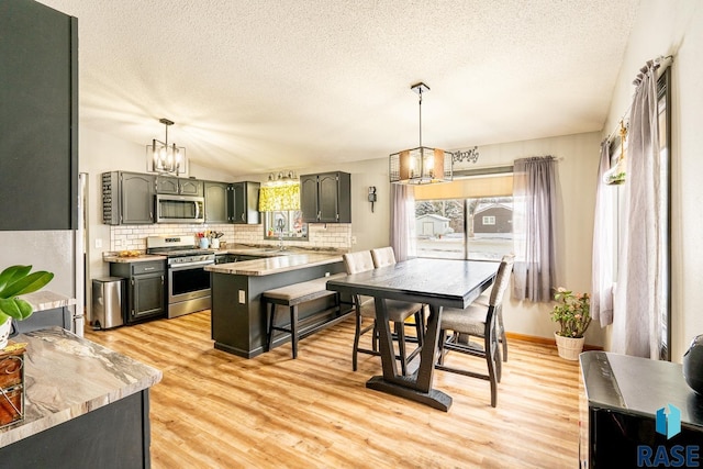 kitchen with decorative light fixtures, light hardwood / wood-style flooring, and stainless steel appliances