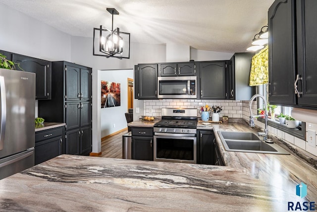 kitchen featuring pendant lighting, sink, appliances with stainless steel finishes, backsplash, and dark hardwood / wood-style flooring