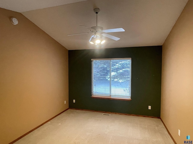 empty room featuring lofted ceiling, ceiling fan, and carpet