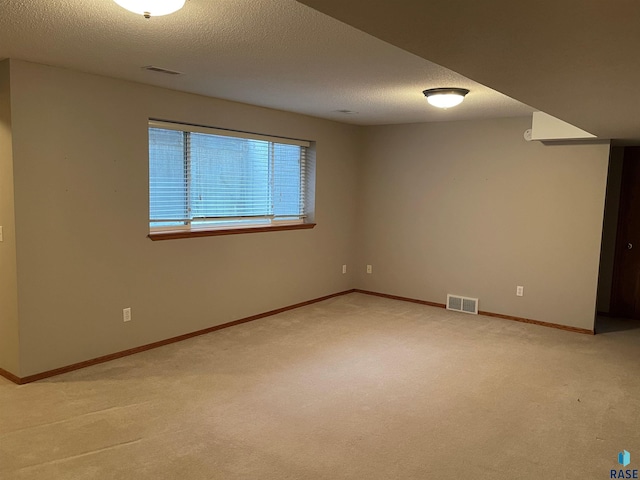 spare room featuring light carpet and a textured ceiling