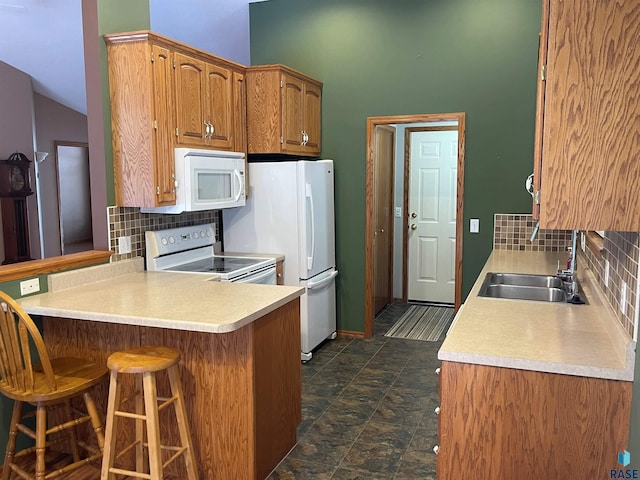 kitchen featuring white appliances, a kitchen breakfast bar, kitchen peninsula, and sink