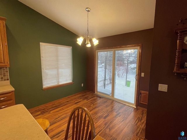 dining room with vaulted ceiling, a notable chandelier, and dark hardwood / wood-style flooring