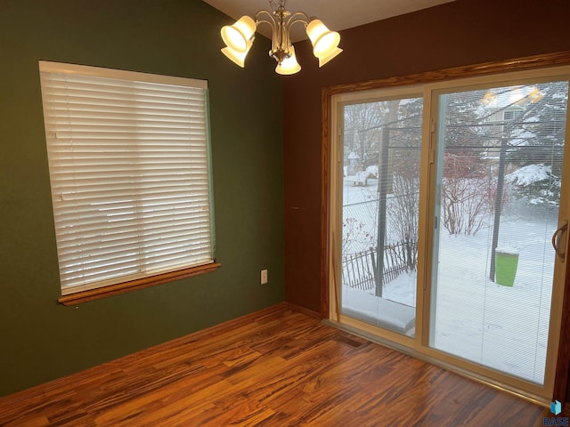 empty room with dark wood-type flooring and a chandelier