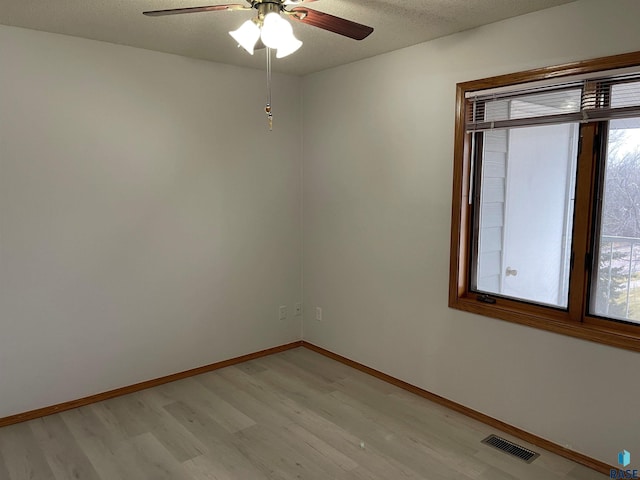 unfurnished room featuring ceiling fan, light hardwood / wood-style floors, and a textured ceiling