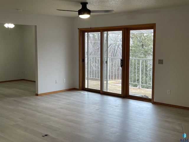 spare room featuring ceiling fan, plenty of natural light, light hardwood / wood-style floors, and a textured ceiling