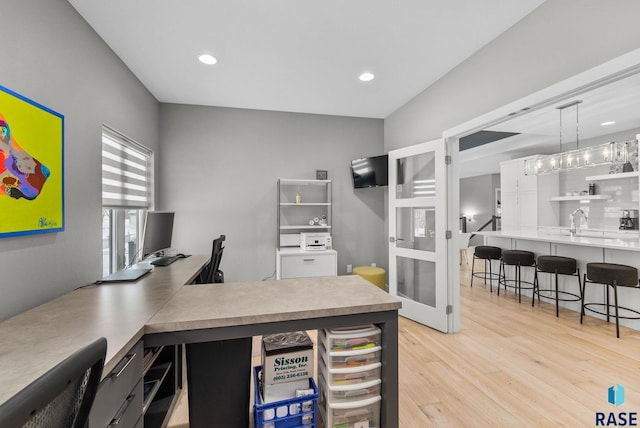 kitchen with hanging light fixtures, french doors, a kitchen bar, and light hardwood / wood-style floors