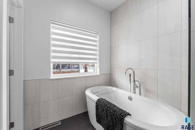 bathroom with a washtub and tile walls